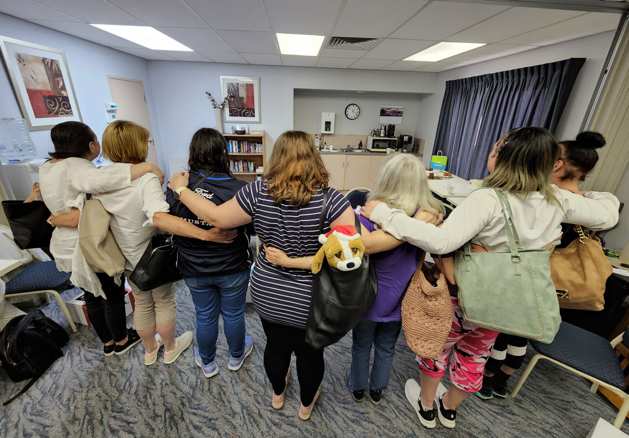 A group of women standing linking arms with their backs to the camera